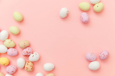 Mutlu Paskalya konsepti. Paskalya şekeri çikolata yumurta ve Jellybean tatlılar trendy pastel pembe arka planda izole. Basit minimalizm düz üst görünüm kopya alanı yatıyordu