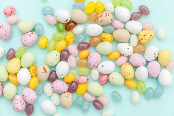 Happy Easter concept. Preparation for holiday. Easter candy chocolate eggs and jellybean sweets isolated on trendy pastel blue background. Simple minimalism flat lay top view copy space. — Stock Photo, Image