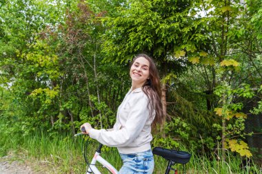 Yaz şehir parkı açık havada bisiklete binen genç kadın. Aktif insanlar. Hipster kız dinlenmek ve binici bisiklet