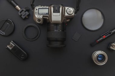 DSR kamera sistemi olan fotoğrafçı işyeri, kamera temizleme seti, siyah masa arka planında lens ve kamera aksesuarı. Hobi seyahat fotoğrafçılık konsepti. Düz görünüm kopyalama alanı.