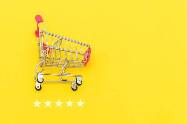 Malý nákupní vozík s potravinami pro nákupní hračky s kolečky a 5 hvězdičkami izolované na žlutém pozadí. Maloobchodní spotřebitel nákup on-line posouzení a přezkoumání koncepce. — Stock fotografie