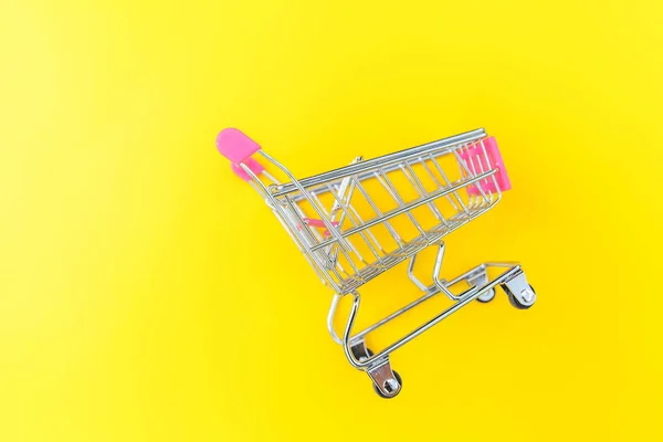 Pequeño supermercado carrito de compras empuje para juguete de compras con ruedas aisladas en amarillo colorido moderno fondo de moda. Venta comprar centro comercial concepto de consumidor tienda. Copiar espacio . — Foto de Stock