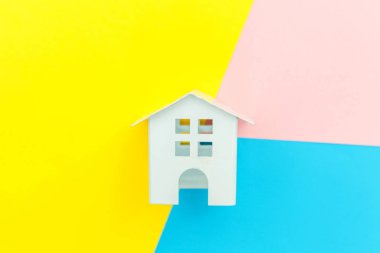 Mavi sarı renkli renkli renkli geometrik arka planda izole edilmiş minyatür beyaz oyuncak evi olan tasarım ipotekli ev kredisi hayali ev konsepti. Düz görünüm kopyalama alanı.