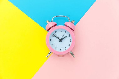 Çalan ikiz çan klasik alarm saati mavi pembe renkli renkli geometrik arkaplanda izole edilmiş. Hayatın dinlenme saatleri. İyi sabahlar. Uyanık kalma kavramı. Düz görünüm kopyalama alanı.