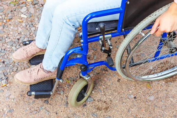 Legs feet handicap woman in wheelchair wheel on road in hospital park waiting for patient services. Unrecognizable paralyzed girl in invalid chair for disabled people outdoors. Rehabilitation concept.