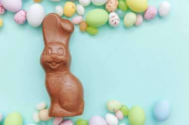 Mutlu Paskalya konsepti. Tatile hazırlık. Paskalya şeker çikolata yumurta tavşan ve jellybean tatlılar trendy pastel mavi arka plan izole. Basit minimalizm düz üst görünüm kopyalama alanı yatıyordu.