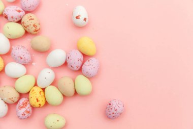 Mutlu Paskalya konsepti. Paskalya şekeri çikolata yumurta ve Jellybean tatlılar trendy pastel pembe arka planda izole. Basit minimalizm düz üst görünüm kopya alanı yatıyordu