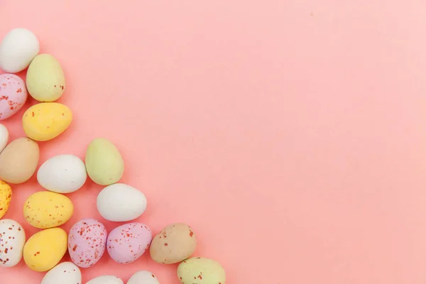 Feliz concepto de Pascua. Huevos de chocolate con caramelos de Pascua y dulces de gelatina aislados sobre un fondo rosa pastel de moda. Minimalismo simple plano laico vista superior copia espacio — Foto de Stock