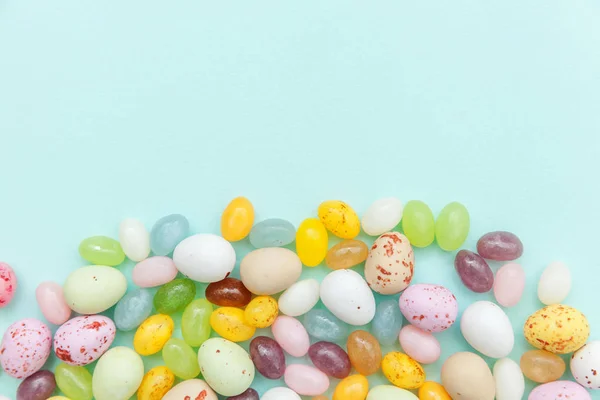 Feliz concepto de Pascua. Preparación para las vacaciones. Huevos de chocolate con caramelos de Pascua y dulces de gelatina aislados sobre un fondo azul pastel de moda. Minimalismo simple plano laico vista superior copia espacio. — Foto de Stock