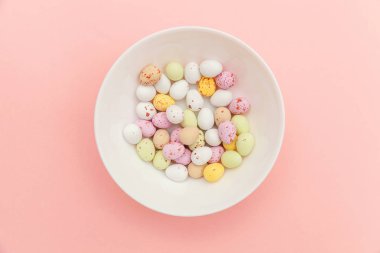 Mutlu Paskalya konsepti. Paskalya şekeri çikolata yumurta ve Jellybean tatlılar trendy pastel pembe arka planda izole. Basit minimalizm düz üst görünüm kopya alanı yatıyordu