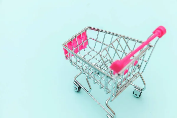 Pequeño supermercado carrito de compras empuje para juguete de compras con ruedas aisladas en azul pastel colorido fondo de moda Copiar el espacio. Venta comprar centro comercial tienda concepto de consumidor. —  Fotos de Stock