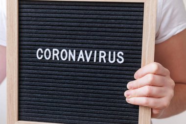 Woman hand holding black letter board with text phrase Coronavirus. Novel coronavirus 2019-nCoV, MERS-Cov middle East respiratory syndrome coronavirus originating in Wuhan China