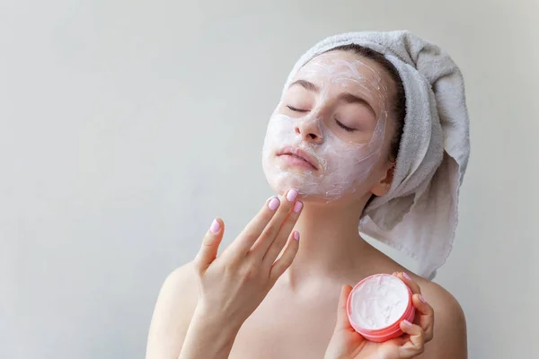 Skönhetsporträtt av kvinna i handduk på huvudet med vit närande mask eller creme i ansiktet, vit bakgrund isolerad. Hudvård eko ekologisk kosmetisk spa slappna av koncept. — Stockfoto