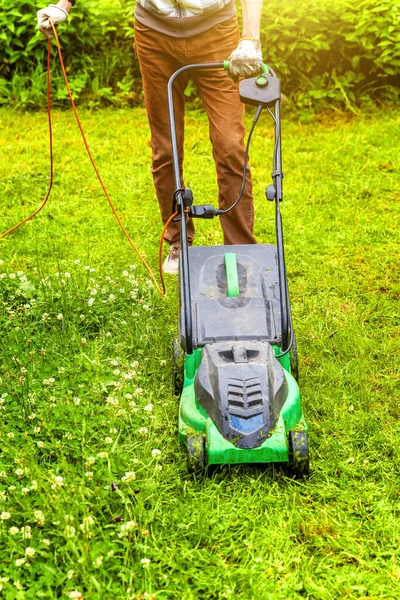 Hombre cortando hierba verde con cortacésped en el patio trasero. Jardinería país estilo de vida fondo. Hermosa vista sobre césped de hierba verde fresca a la luz del sol, paisaje de jardín en primavera o verano. — Foto de Stock