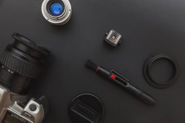 DSR kamera sistemi olan fotoğrafçı işyeri, kamera temizleme seti, siyah masa arka planında lens ve kamera aksesuarı. Hobi seyahat fotoğraf konsepti Düz görünüm kopya alanı yatıyordu