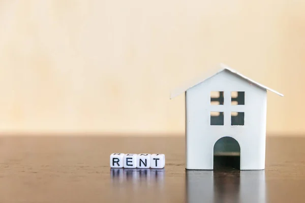 Miniatur-Spielzeugmodellhaus mit Inschrift Mietbuchstaben Wort auf Holzkulisse. Ökodorf, abstrakter ökologischer Hintergrund. Immobilien Hypothek Immobilienversicherung Sweet Home Ökologie Mietkonzept — Stockfoto