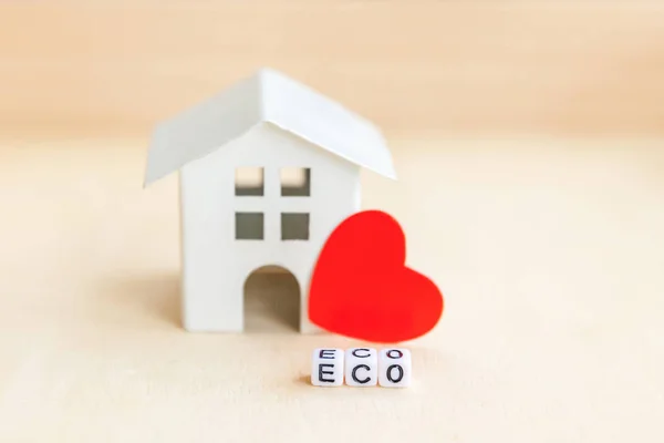 Miniature toy model house with inscription ECO letters word on wooden backdrop. Eco Village, abstract environmental background. Ecology zero waste social responsibility recycle bio home concept
