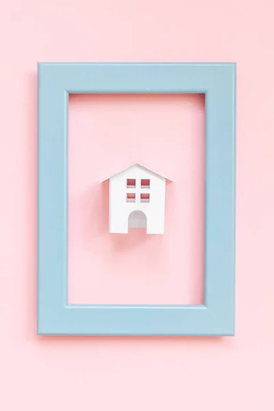 Po prostu zaprojektować z miniaturowym białym domu zabawka w niebieskiej ramce na białym tle różowy pastelowy kolorowy tło — Zdjęcie stockowe