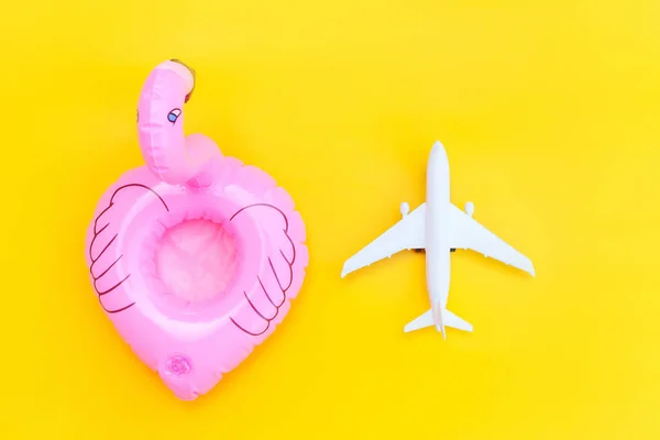 Zomer strand compositie. Minimale eenvoudige flat lag met vlak en opblaasbare flamingo geïsoleerd op gele achtergrond. Vakantie reizen avontuur reis concept. Bovenaanzicht kopieerruimte. — Stockfoto