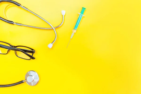 Equipamento médico estetoscópio ou óculos de fonendoscópio e seringa isolados em fundo amarelo moderno — Fotografia de Stock