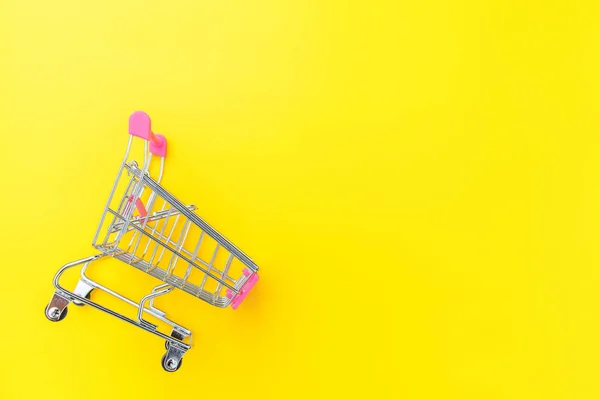 Pequeño supermercado carrito de compras empuje para juguete de compras con ruedas aisladas en amarillo colorido moderno fondo de moda. Venta comprar centro comercial concepto de consumidor tienda. Copiar espacio . — Foto de Stock