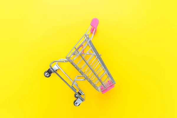 Small supermarket grocery push cart for shopping toy with wheels isolated on yellow colourful trendy modern fashion background. Sale buy mall market shop consumer concept. Copy space. — Stock Photo, Image