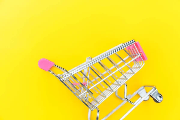 Kleiner Supermarkt-Einkaufswagen zum Einkaufen Spielzeug mit Rädern isoliert auf gelben bunten trendigen modernen Modehintergrund. Verkauf kaufen Einkaufszentrum Marktladen Verbraucherkonzept. Kopierraum. — Stockfoto