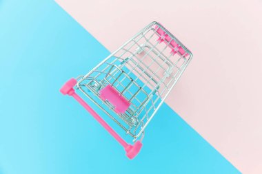 Küçük süpermarket bakkal mavi ve pembe pastel renkli trendy geometrik arka plan Copy alanı izole tekerlekleri ile alışveriş oyuncak için sepet itin. Satılık alışveriş merkezi market shop tüketici konsepti satın.