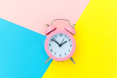 Çalan ikiz çan klasik alarm saati mavi pembe renkli renkli geometrik arkaplanda izole edilmiş. Hayatın dinlenme saatleri. İyi sabahlar. Uyanık kalma kavramı. Düz görünüm kopyalama alanı.