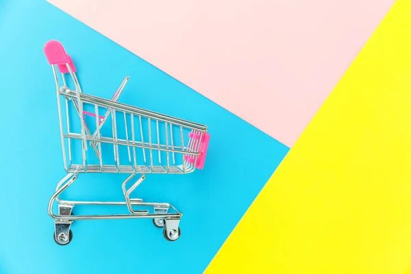 Pequeño supermercado carrito de compras empuje para juguete de compras con ruedas aisladas en azul amarillo pastel colorido fondo geométrico de moda Copiar el espacio. Venta comprar centro comercial tienda concepto de consumidor . — Foto de Stock