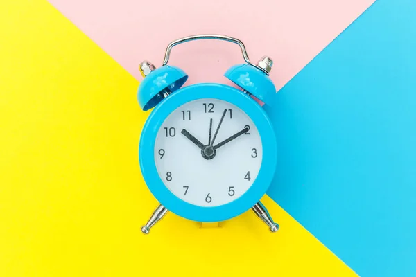 Ringande dubbla klocka klassiska väckarklocka isolerad på blå gul rosa pastell färgglada geometriska bakgrund. Vilotid god morgon natt vakna upp koncept. Platt låg ovanifrån kopiera utrymme. — Stockfoto
