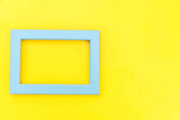 Design simple avec cadre bleu vide isolé sur fond jaune coloré et tendance. Vue de dessus, plan plat, espace de copie, maquette. Concept minimal . — Photo