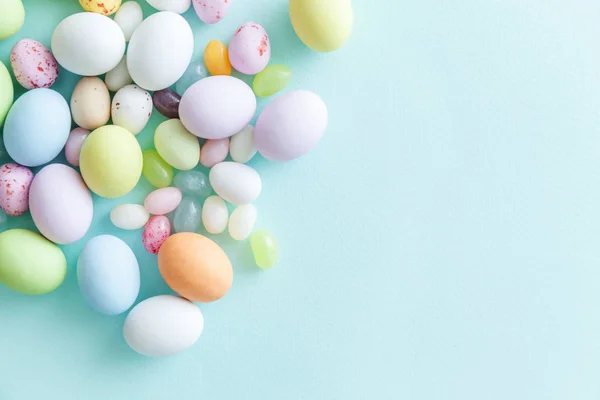 Feliz concepto de Pascua. Preparación para las vacaciones. Huevos de chocolate con caramelos de Pascua y dulces de gelatina aislados sobre un fondo azul pastel de moda. Minimalismo simple plano laico vista superior copia espacio. — Foto de Stock