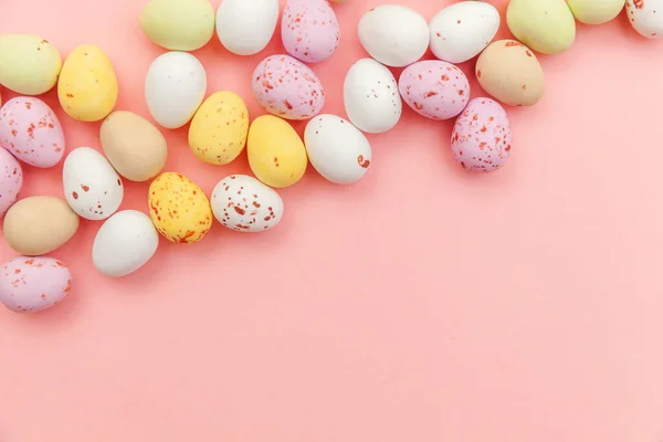 Feliz concepto de Pascua. Huevos de chocolate con caramelos de Pascua y dulces de gelatina aislados sobre un fondo rosa pastel de moda. Minimalismo simple plano laico vista superior copia espacio — Foto de Stock