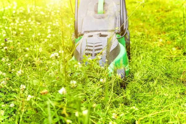 Człowiek przycinający zieloną trawę kosiarką na podwórku. Ogrodnictwo kraju tle stylu życia. Piękny widok na świeżą zieloną trawnik w świetle słonecznym, krajobraz ogrodowy w sezonie wiosennym lub letnim. — Zdjęcie stockowe