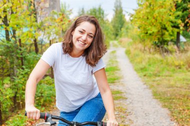 Yazlık şehir parkında bisiklet süren genç bir kadın. Aktif insanlar. Hippi kız rahatla ve bisiklete bin. Yaz günü işe bisikletle gitmek. Bisiklet ve ekoloji yaşam tarzı kavramı.