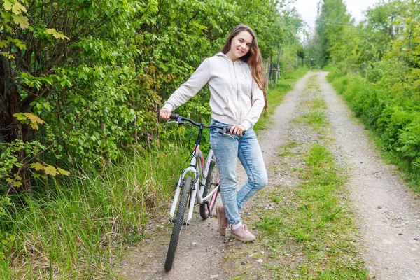 Young woman riding bicycle in summer city park outdoors. Active people. Hipster girl relax and rider bike