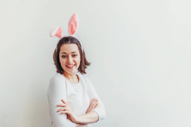 Mutlu Paskalya bayramı bahar kutlamaları. Beyaz arka planda izole edilmiş tavşan kulağı takan genç bir kadın. Tatil için hazırlık. Mutlu ve heyecanlı görünen bir kız Paskalya gününde eğleniyor.