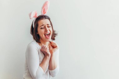 Mutlu Paskalya bayramı bahar kutlamaları. Beyaz arka planda izole edilmiş tavşan kulağı takan genç bir kadın. Tatil için hazırlık. Mutlu ve heyecanlı görünen bir kız Paskalya gününde eğleniyor.