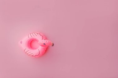 Yaz kumsalı kompozisyonu. Pastel pembe arka planda izole edilmiş şişme flamingo tasarımı. Havuz şamandırası partisi, ünlü modası konsepti. Düz görünüm kopyalama alanı.