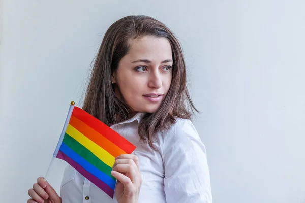 白地にLGBTの虹の旗が描かれた美しい白人レズビアンの女の子は幸せそして興奮しています。若い女性ゲイの誇りの肖像画。lgbtqコミュニティの概念に対する平等な権利. — ストック写真