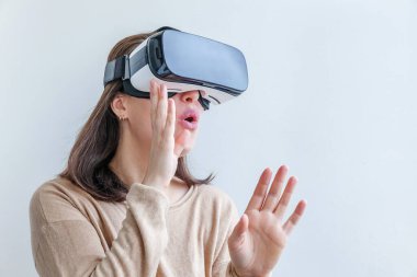 Beyaz arka planda sanal gerçeklik gözlüğü başlığı takan genç kadın gülümse. Sanal gerçeklik gözlüğü takan akıllı telefon. Teknoloji, simülasyon, yüksek teknoloji, video oyunu konsepti