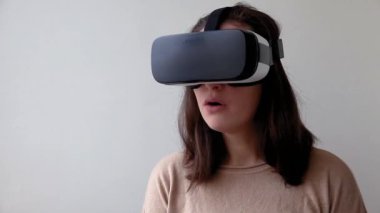 Beyaz arka planda sanal gerçeklik gözlüğü başlığı takan genç kadın gülümse. Sanal gerçeklik gözlüğü takan akıllı telefon. Teknoloji, simülasyon, yüksek teknoloji, video oyunu konsepti