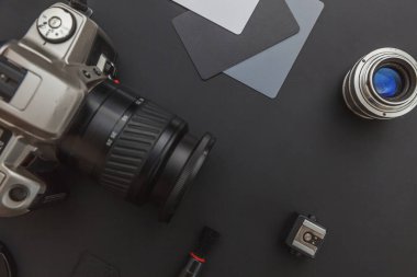 DSR kamera sistemi olan fotoğrafçı işyeri, kamera temizleme seti, siyah masa arka planında lens ve kamera aksesuarı. Hobi seyahat fotoğrafçılık konsepti. Düz görünüm kopyalama alanı