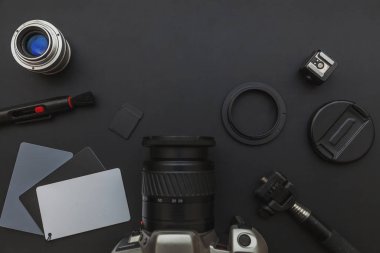 DSR kamera sistemi olan fotoğrafçı işyeri, kamera temizleme seti, siyah masa arka planında lens ve kamera aksesuarı. Hobi seyahat fotoğrafçılık konsepti. Düz görünüm kopyalama alanı