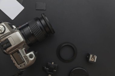 DSR kamera sistemi olan fotoğrafçı işyeri, kamera temizleme seti, siyah masa arka planında lens ve kamera aksesuarı. Hobi seyahat fotoğrafçılık konsepti. Düz görünüm kopyalama alanı