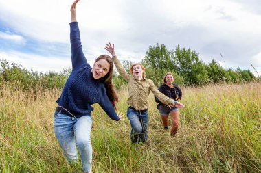 Yaz tatili mutlu insanlar konsepti. Üç arkadaş grubu erkek ve iki kız dışarıda koşup eğleniyorlar. Arkadaşlarla pikniğe gidiyoruz.