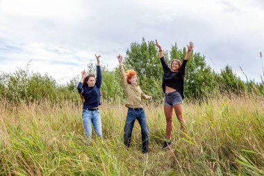 Yaz tatili mutlu insanlar konsepti. Üç arkadaş grubu erkek ve iki kız dans ediyor ve dışarıda birlikte eğleniyorlar. Arkadaşlarla pikniğe gidiyoruz.