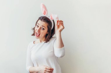 Mutlu Paskalya bayramı bahar kutlamaları. Beyaz arka planda izole edilmiş tavşan kulağı takan genç bir kadın. Tatil için hazırlık. Mutlu ve heyecanlı görünen bir kız, Paskalya gününde eğleniyor.
