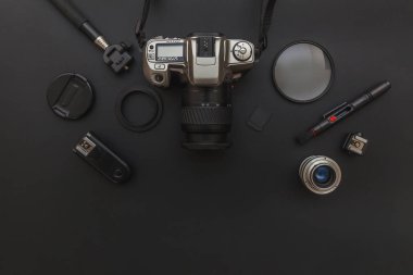 DSR kamera sistemi olan fotoğrafçı işyeri, kamera temizleme seti, siyah masa arka planında lens ve kamera aksesuarı. Hobi seyahat fotoğrafçılık konsepti. Düz görünüm kopyalama alanı